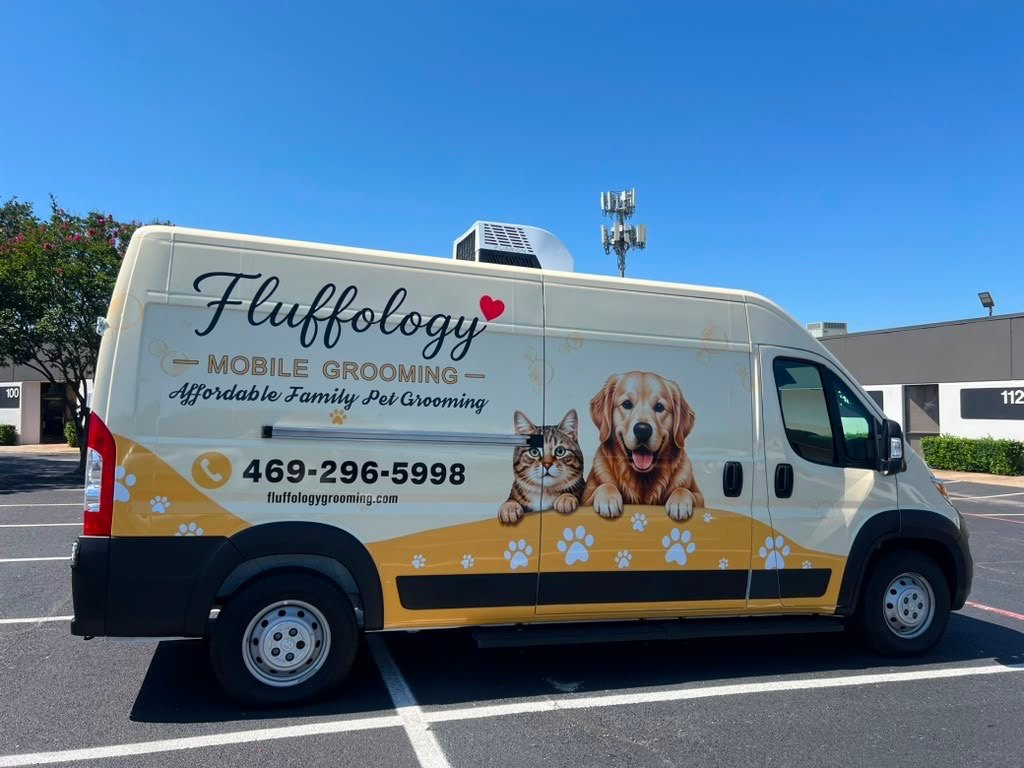 Fluffology's cream and gold grooming van with a dog and cat painted on the side